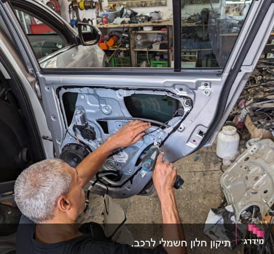אדם מתקן דלת רכב עם כלי עבודה